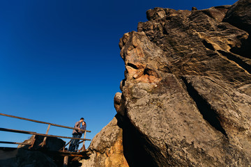 Nice couple standing at the enormous huge rock