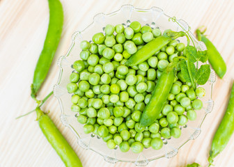 green peas in bowl on wood light