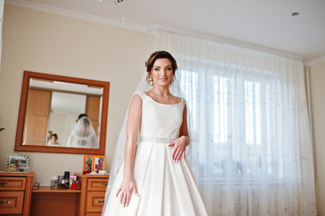Portrait of a fantastic bride posing in her room on the wedding day.