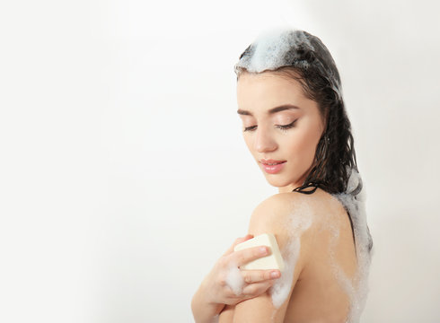 Young woman taking shower on white background