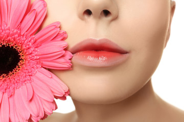 Young woman with beautiful lips and gerbera flower near face, closeup