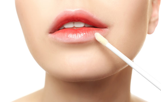 Young woman applying lip gloss, closeup