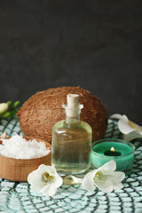 Fototapeta na wymiar Bottle with oil, desiccated coconut and candle on grey background