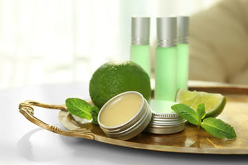 Tray with perfumes, limes and mint leaves on table