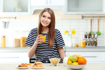 Young beautiful woman having breakfast at kitchen