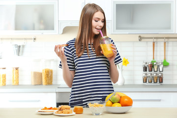 Young beautiful woman having breakfast at kitchen