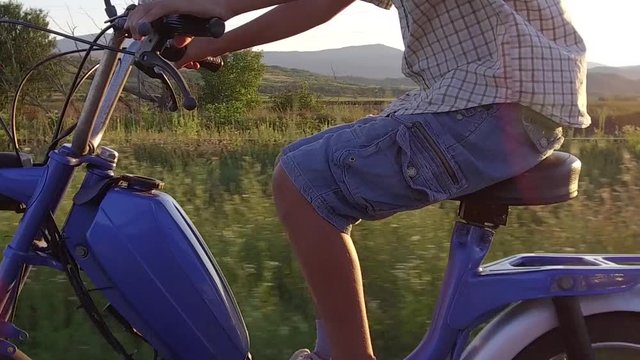 Boy drive moped at sunset