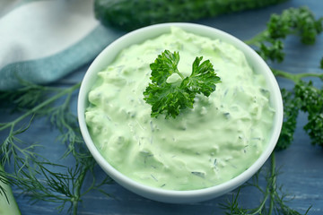 Delicious yogurt sauce in bowl with ingredients on wooden background