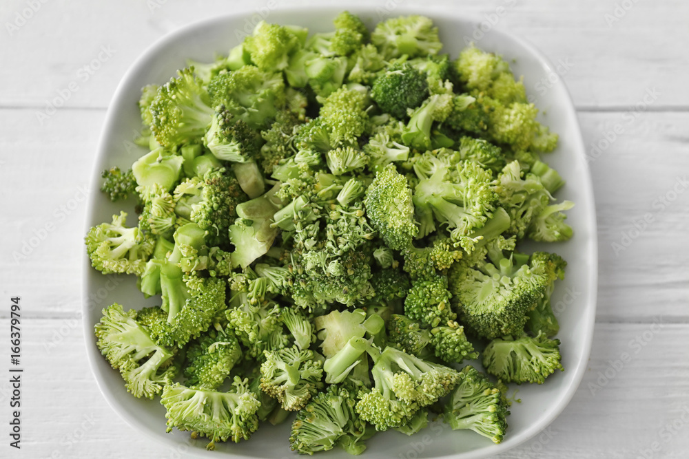 Poster plate with fresh chopped broccoli on white wooden background, closeup