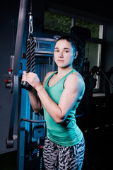 Fototapeta na wymiar Young sexy fitness woman workout with training machine in the gym