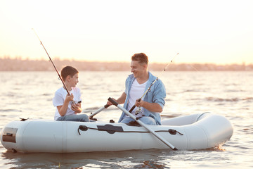 Dad and son fishing from inflatable boat on river © Africa Studio