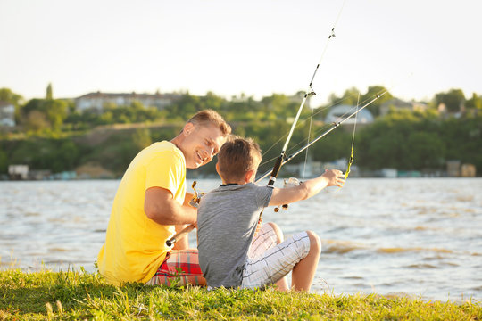 Dad and son fishing from shore on river