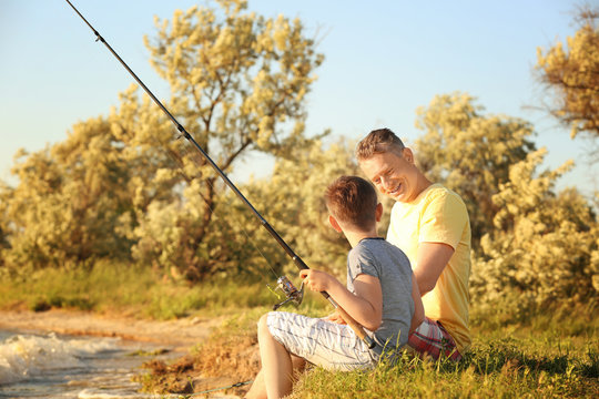 Dad and son fishing from shore on river