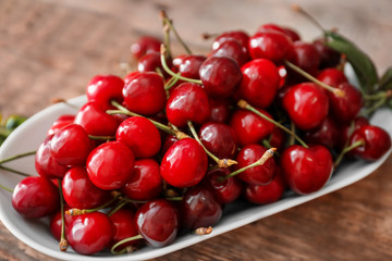Plate with fresh ripe cherries on wooden table