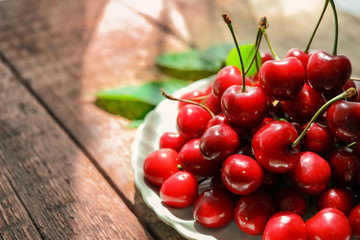 Plate with fresh ripe cherries on wooden table
