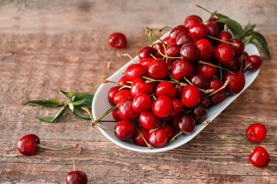 Plate with fresh ripe cherries on wooden table