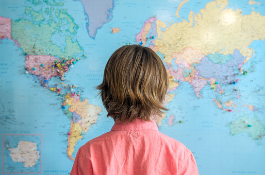 Child Stands Looking At A Map Of The World