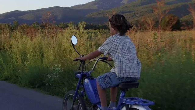 Boy ride moped at sunset