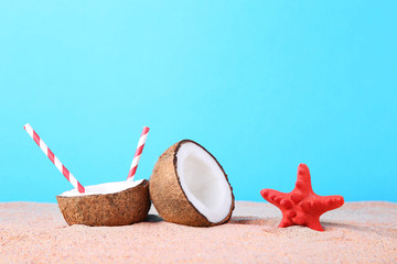 Fototapeta na wymiar Half of coconut with starfish on beach sand