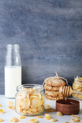 Cornflakes, bottle of milk and bowl of honey on wooden table