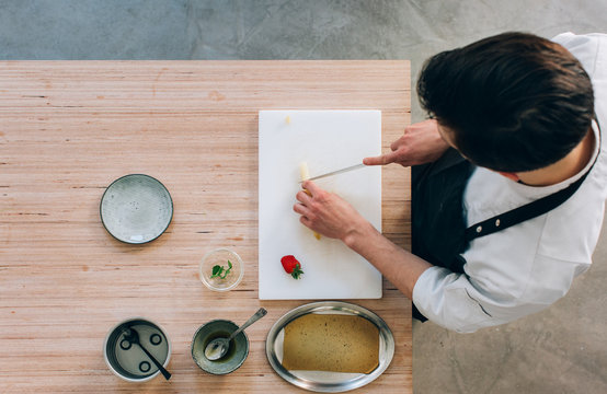 Young Caucasian Pastry Chef Cutting Asparagus For Experimental Dessert