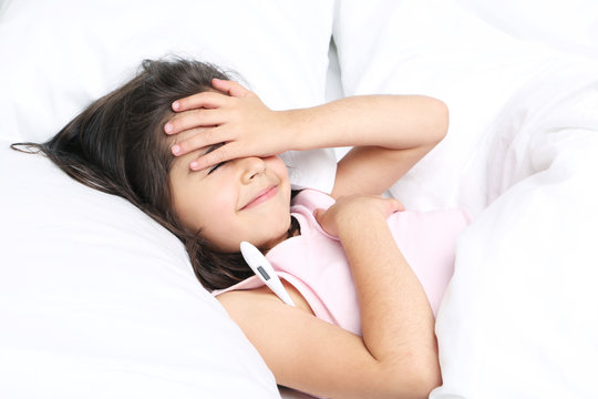 Sick little girl with thermometer in white bed