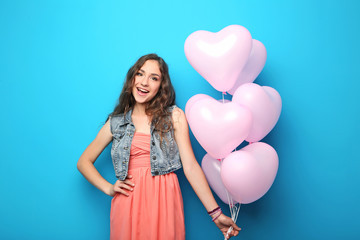 Portrait of young woman with pink heart balloon on blue background