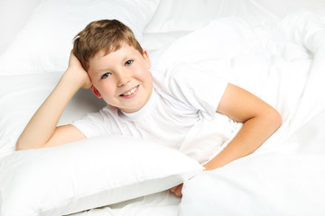 Young boy lying in white bed