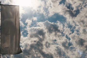 Empty white clear flag waving against sun and cloudy blue sky, close up