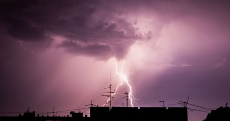 Naklejka na ściany i meble Thunderstorm lightning over city buildings