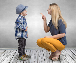 A young mother scolds her naughty little son.Boy showing tongue and teases mom.	