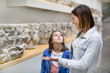 Mother and daughter exploring bas-reliefs in museum