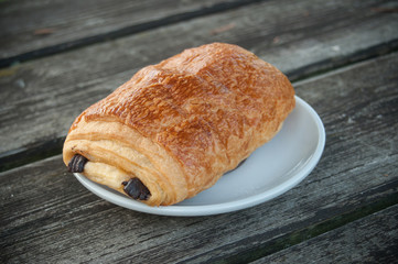 petit pain au chocolat dans une assiette sur une table en bois