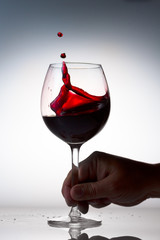 Someone Hand holding glass of red wine with splash