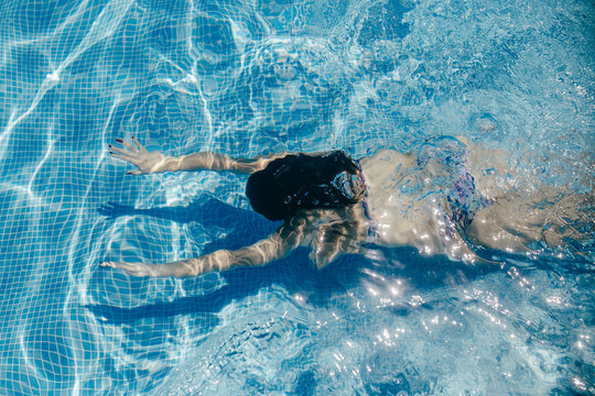 .Young woman enjoying the pool on a sunny summer day. Taking photos under water playful. Lifestyle portrait.