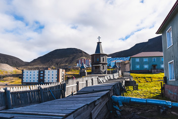 Landscape of the Russian Orthodox wooden church in the city of Barentsburg on the Spitsbergen archipelago in the summer in the Arctic - obrazy, fototapety, plakaty