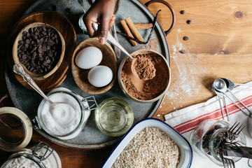 Hand of a black girl placing two eggs in a tray with cookie ingredients