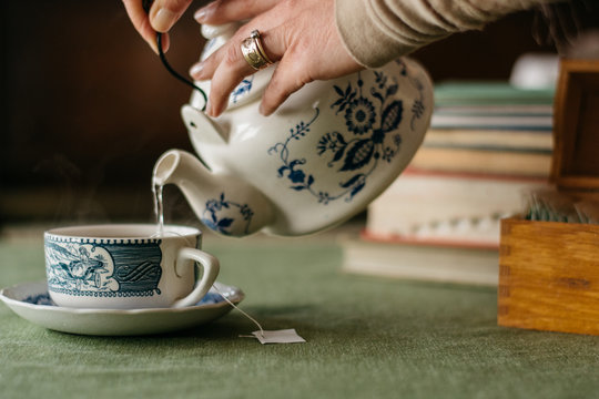 Woman's hands pouring hot water from a teapot in a tea cup