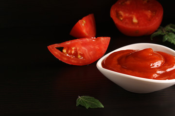 Ketchup on a black background and tomato basil