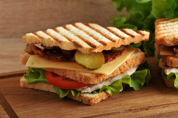 multilayered sandwich with cheese, ham, tomatoes, pickles and lettuce photographed closeup