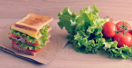 multilayered sandwich with cheese, ham, tomatoes and lettuce