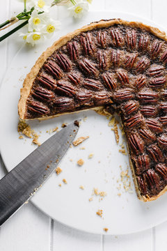 whole pecan pie with a knife and a few pieces missing
