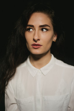 Pretty woman in white button up shirt, septum piercing and long dark hair