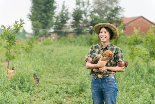 Female farmer holding chicken