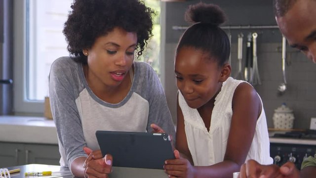 Mother Helping Daughter With Homework In Kitchen