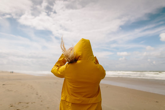 Woman on a windy beach wearing a yellow raincoat