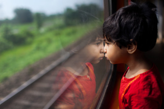 Little girl looking through the train window in a contemplative mood