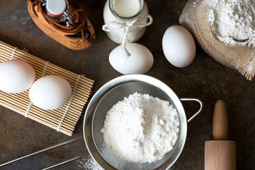 Ingredients for baking - milk, eggs, flour, oil on brown marble background. copy space