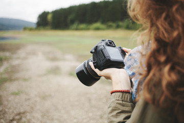 Young woman reviewing her photographs on dslr camera in the mountain