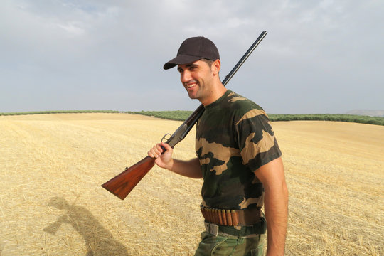 Young hunter holding a shotgun in the countryside